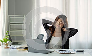 Young Asian businesswoman stretching arms raised relaxing at the office.