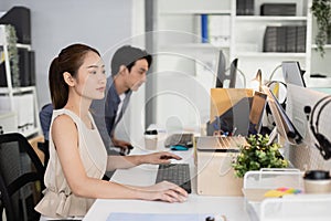 Young asian businesswoman using laptop at office table. company employees sitting at work, Accounting staff working towards