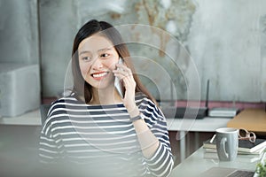 Young Asian businesswoman using smartphone to interact with customers in the office.