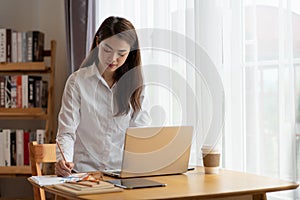 Young Asian businesswoman working at her house with laptop, working at home, business concept