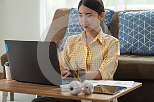 Young Asian businesswoman working with laptop at her house, work from home, business concept