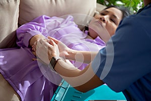 Young asian caregiver woman or doctor encourage and care senior while lying on sofa in living room.