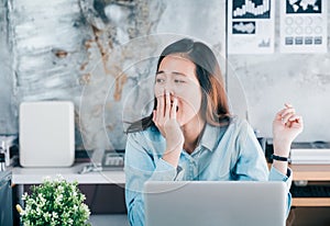 Young asian casual businesswoman yawn in front of laptop compute