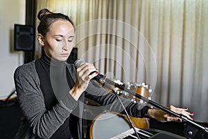 Young Asian or Caucasian woman sets up tunes microphone prepares to sing