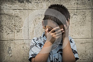 A young Asian child covering his face with his arms