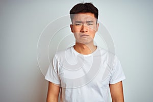 Young asian chinese man wearing t-shirt standing over isolated white background depressed and worry for distress, crying angry and