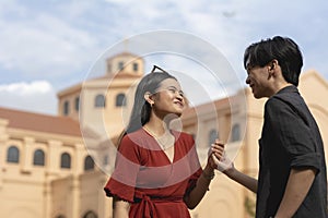 A young asian Christian couple holding hands in front of a church foreshadowing a future marriage