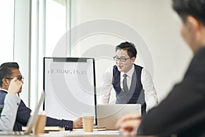 Young asian corporate executive facilitating meeting in office