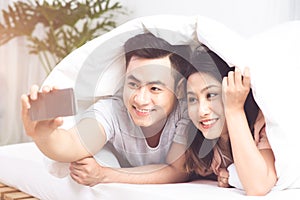 Young asian coule taking selfie photo at home