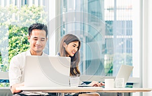 Young Asian couple or college student using laptop computer notebook work together at coffee shop or university campus