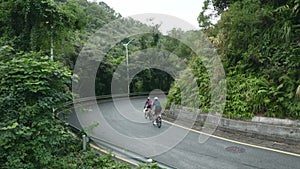 young asian couple cyclists riding bike on rural road