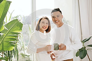 Young asian couple drinking coffee in living room at home