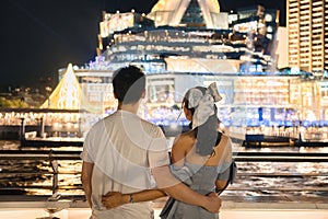 Young asian couple embracing and sightseeing with light show at department store during cruise ship on deck