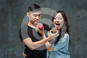 Young asian couple enjoy eating of sweet colorful donut