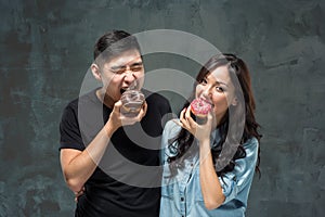 Young asian couple enjoy eating of sweet colorful donut