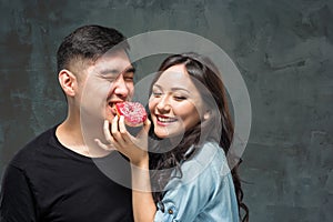 Young asian couple enjoy eating of sweet colorful donut