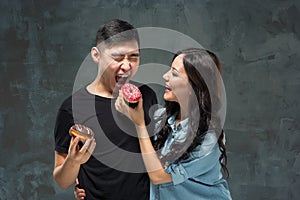 Young asian couple enjoy eating of sweet colorful donut