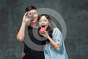 Young asian couple enjoy eating of sweet colorful donut