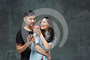 Young asian couple enjoy eating of sweet colorful donut