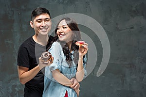 Young asian couple enjoy eating of sweet colorful donut