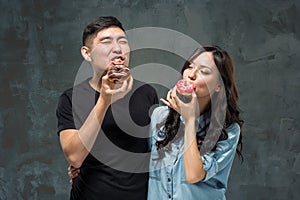 Young asian couple enjoy eating of sweet colorful donut