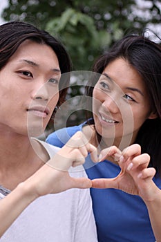 Young Asian couple forming a heart shape