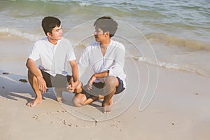 Young asian couple gay smiling romantic drawing heart shape together on sand in vacation