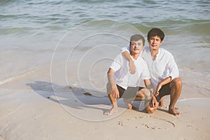 Young asian couple gay smiling romantic drawing heart shape together on sand in vacation