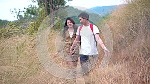 Young Asian couple holding hands enjoying together in golden meadow trail, Couple walking on hills nature outdoor wild grass fores