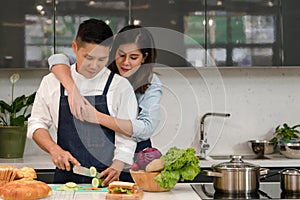 Young asian couple husband and wife having romantic and fun moment during coronavirus pandemic lock down cooking foods together at