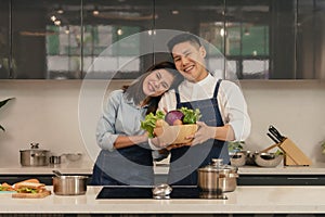 Young asian couple husband and wife having romantic and fun moment during coronavirus pandemic lock down cooking foods together at