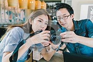 Young Asian couple learning to use mirrorless digital camera together at coffee shop