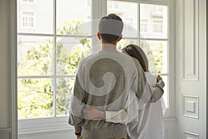 Young asian couple looking out of window