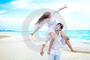 Young asian couple in love honeymoon at sea beach on blue sky. husband giving piggy back ride to wife . happy smiling wedding