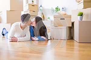 Young asian couple lying on the floor of new house arround cardboard boxes relaxing and smiling happy