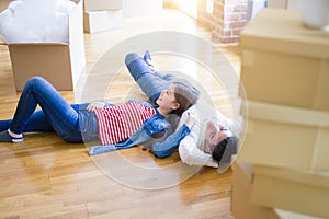 Young asian couple lying on the floor of new house arround cardboard boxes relaxing and smiling happy