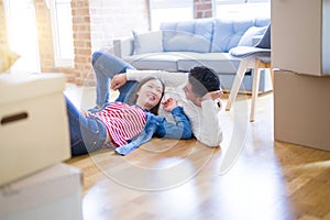 Young asian couple lying on the floor of new house arround cardboard boxes relaxing and smiling happy