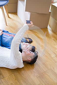 Young asian couple lying on the floor of new house smiling happy taking a selfie photo at new apartment