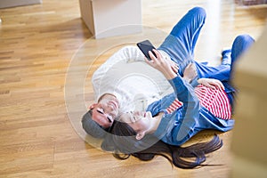 Young asian couple lying on the floor of new house smiling happy taking a selfie photo at new apartment
