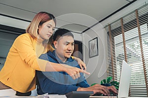 Young asian couple managing finances, reviewing their bank accounts using laptop computer and calculator at modern home. Woman and