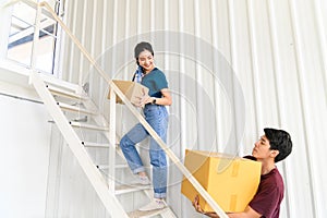 Young asian couple moving and carrying boxes upstairs in new house, celebrating moving to new home concept