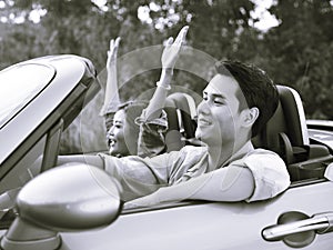 Young asian couple riding in a convertible car photo