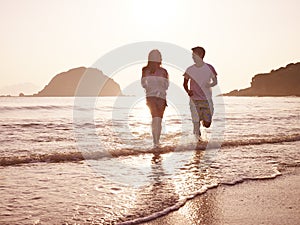 Young asian couple running on beach