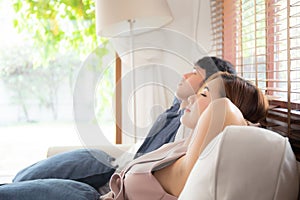 Young asian couple smile relax comfortable on sofa in the living room in holiday, family leisure and resting with happy