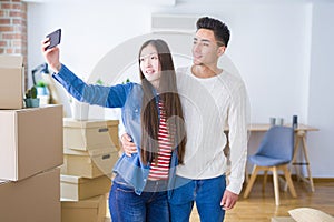 Young asian couple smiling taking a selfie photo with smartphone, moving to a new home together