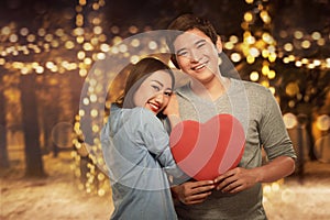 Young asian couple standing in embrace and holding heart shape