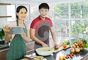 Young Asian couple. Standing smile cooking in the kitchen. prepare salad for food together happily.