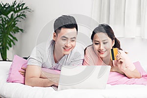 Young asian couple surfing on internet and shopping with laptop