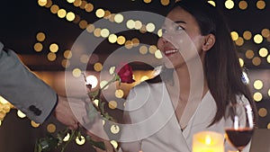 Young asian couple surprise moment with rose flower at romantic dinner in rooftop restaurant at city night with sweet moment