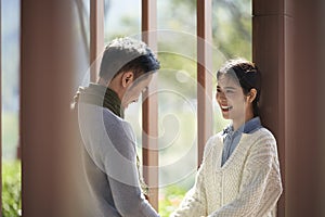 Young asian couple talking chatting outdoors in city park